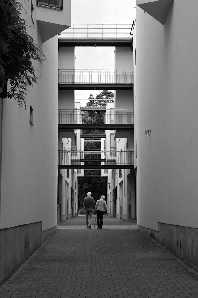 Twee mensen wandelen rustig door een appartementencomplex, beeld bij een zorgvuldige woningontruiming